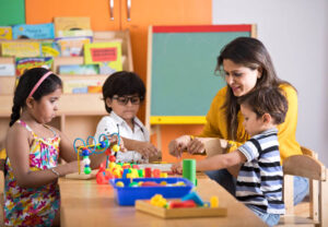 Teachers with children playing and learning at preschool